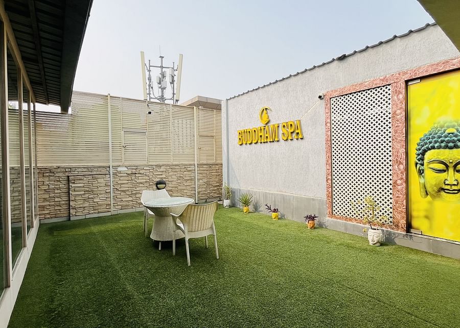 Outdoor seating area at Nemesia with lush greenery and a vibrant mural.