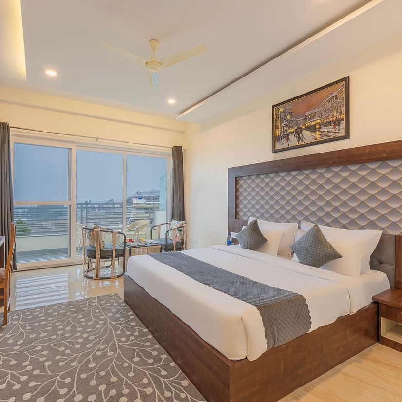 a double bed with a TV opposite it inside one of the rooms - Stone Wood Mountain Resort, Dharamshala - Dharamshala Place to Stay