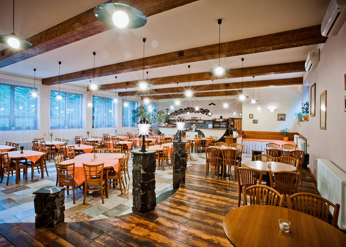 Modern restaurant interior at Paradise Wild Hills Resort with wooden beams, warm lighting, and contemporary dining setup.
