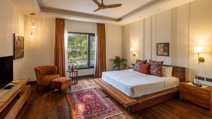 Bedroom with a white bed, wooden floors, and a seating area near a window at Karma Chalets.