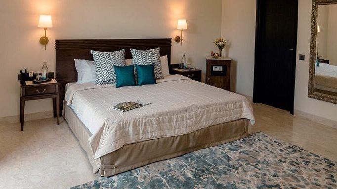 Bedroom with a double bed, bedside tables, lamps, and a blue rug at Karma Chalets.