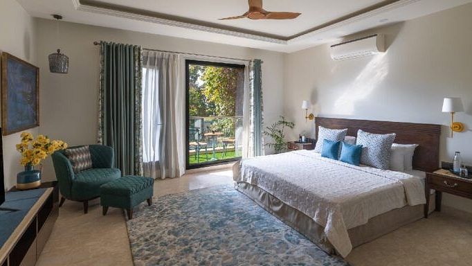 Bright bedroom with a double bed, armchairs, and natural light from large windows at Karma Chalets.