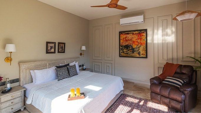 Bedroom with a white bed, wooden furniture, ceiling fan, and a painting on the wall at Karma Chalets.
