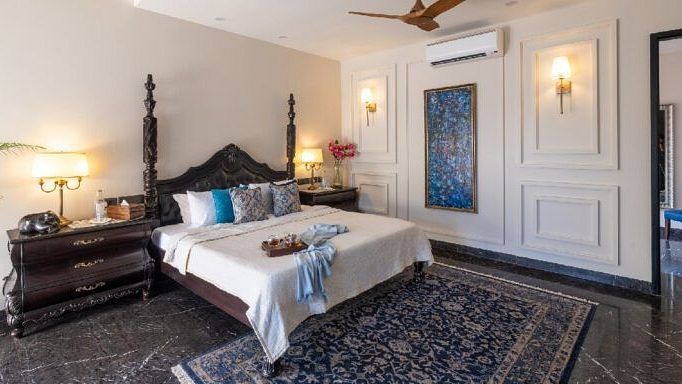 Bedroom with a carved wooden bed frame, dark furnishings, and a patterned rug at Karma Chalets.
