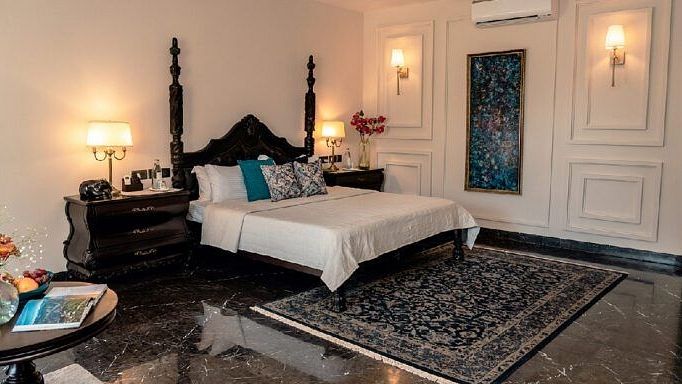 Bedroom with a four-poster bed, teal cushions, and classic wall detailing at Karma Chalets.