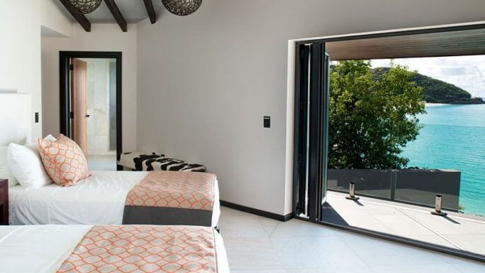 Oceanview bedroom with twin beds and open-air access at Tamarind Hills Resort and Villas, Antigua offering stunning views of the Caribbean Sea.