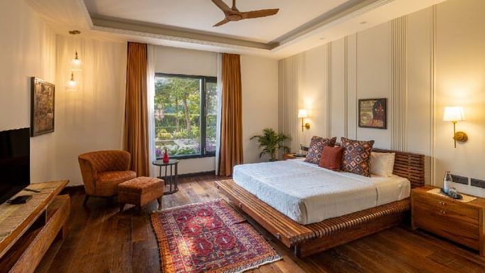 Bedroom with a white bed, wooden floors, and a seating area near a window at Karma Chalets.