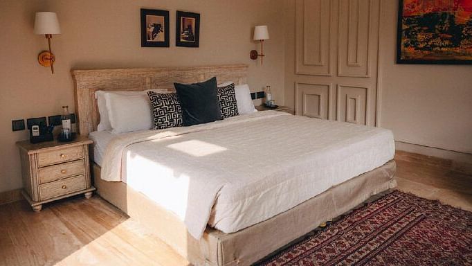 Bedroom with a beige bed, side tables, lamps, and a patterned red rug at Karma Chalets.