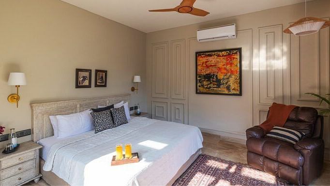 Bedroom with a white bed, wooden furniture, ceiling fan, and a painting on the wall at Karma Chalets.