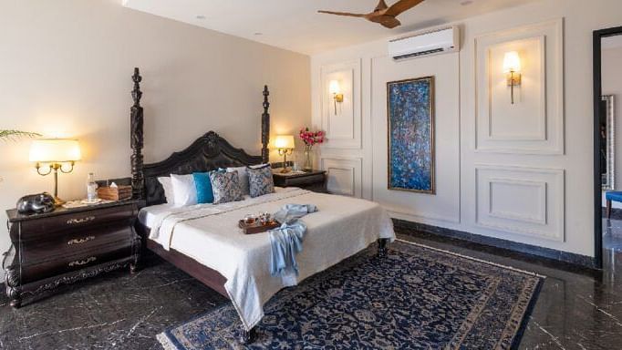Bedroom with a carved wooden bed frame, dark furnishings, and a patterned rug at Karma Chalets.