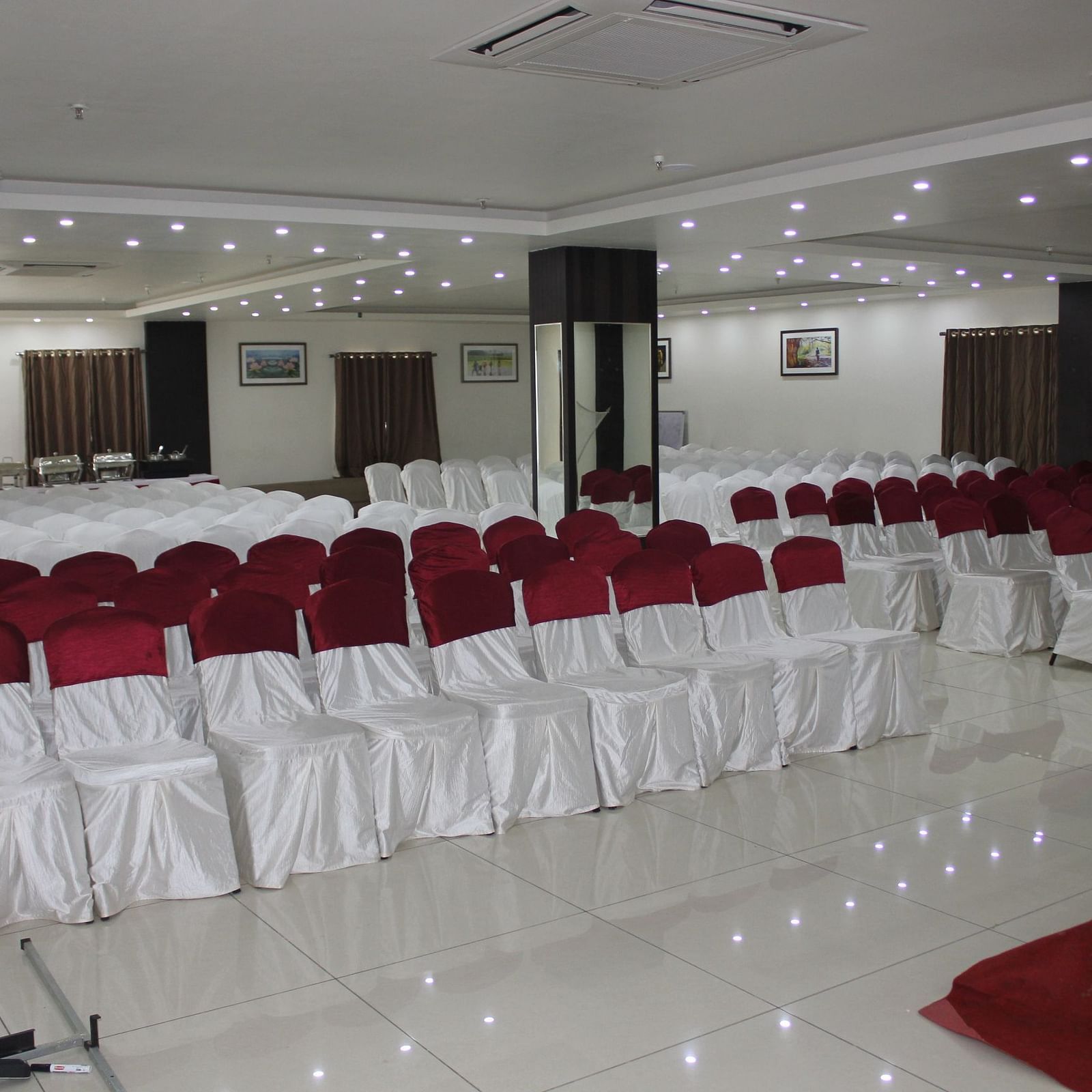 Jyothi hall with seats arranged and lights on the ceiling at Hotel Green Apple