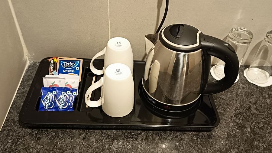 Tea and coffee maker along with a set of glasses and mugs beside sachets of teabags and coffee powder as well as milk powder and sugar inside premium studio at Starlit Suites, Shirdi