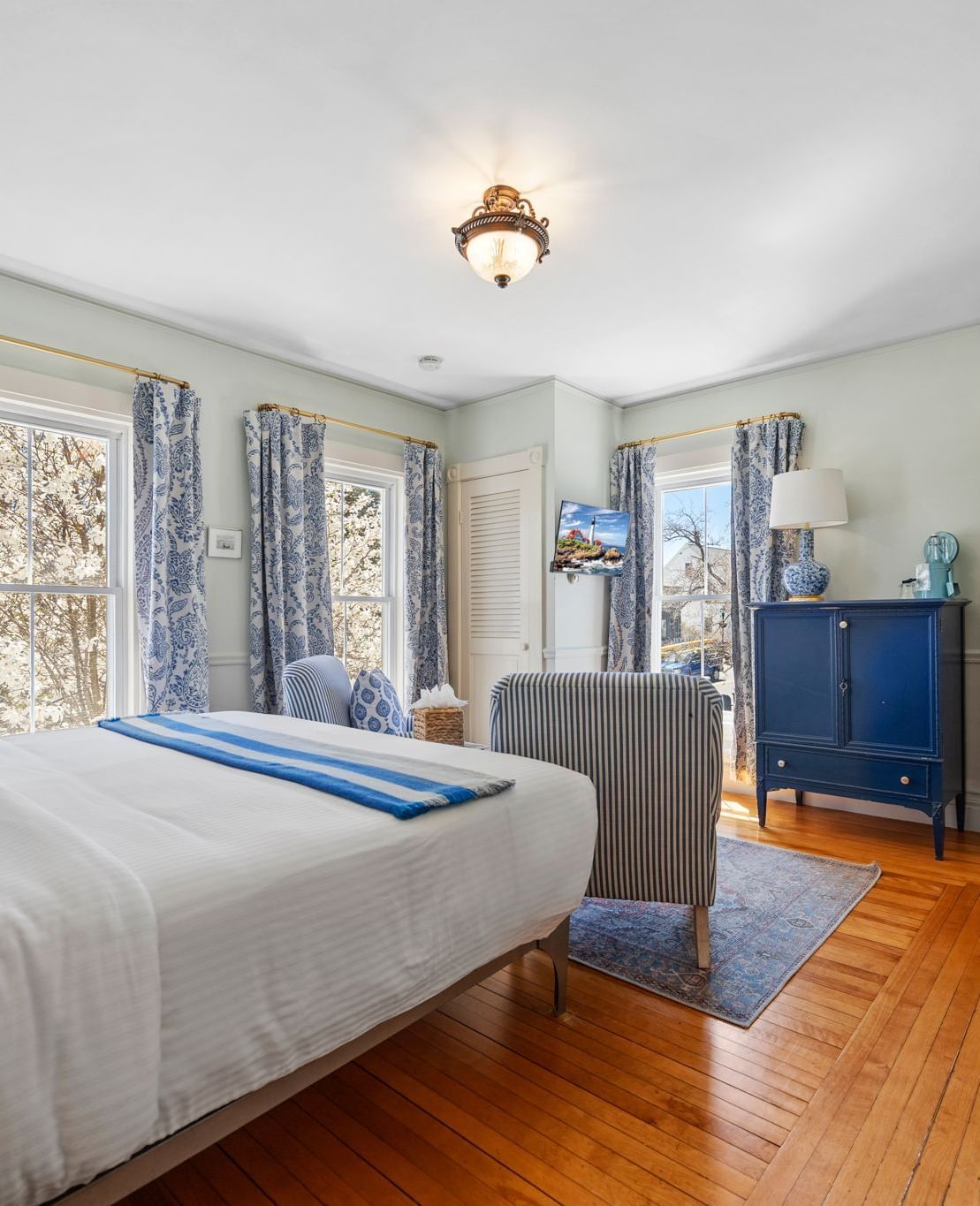 A air conditioned room with queen size bed and floral curtains at Hartstone Inn