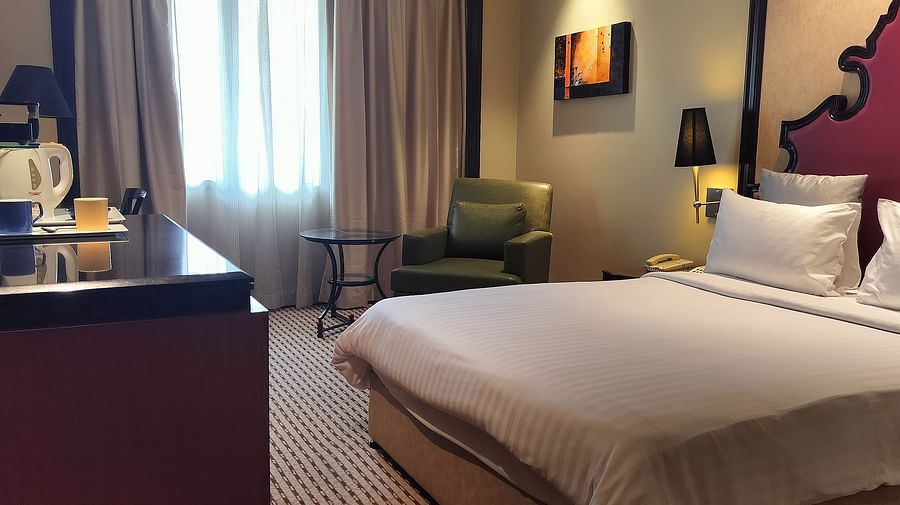 Cosy hotel room featuring a double bed, bedside lamps, a desk area, and natural lighting.