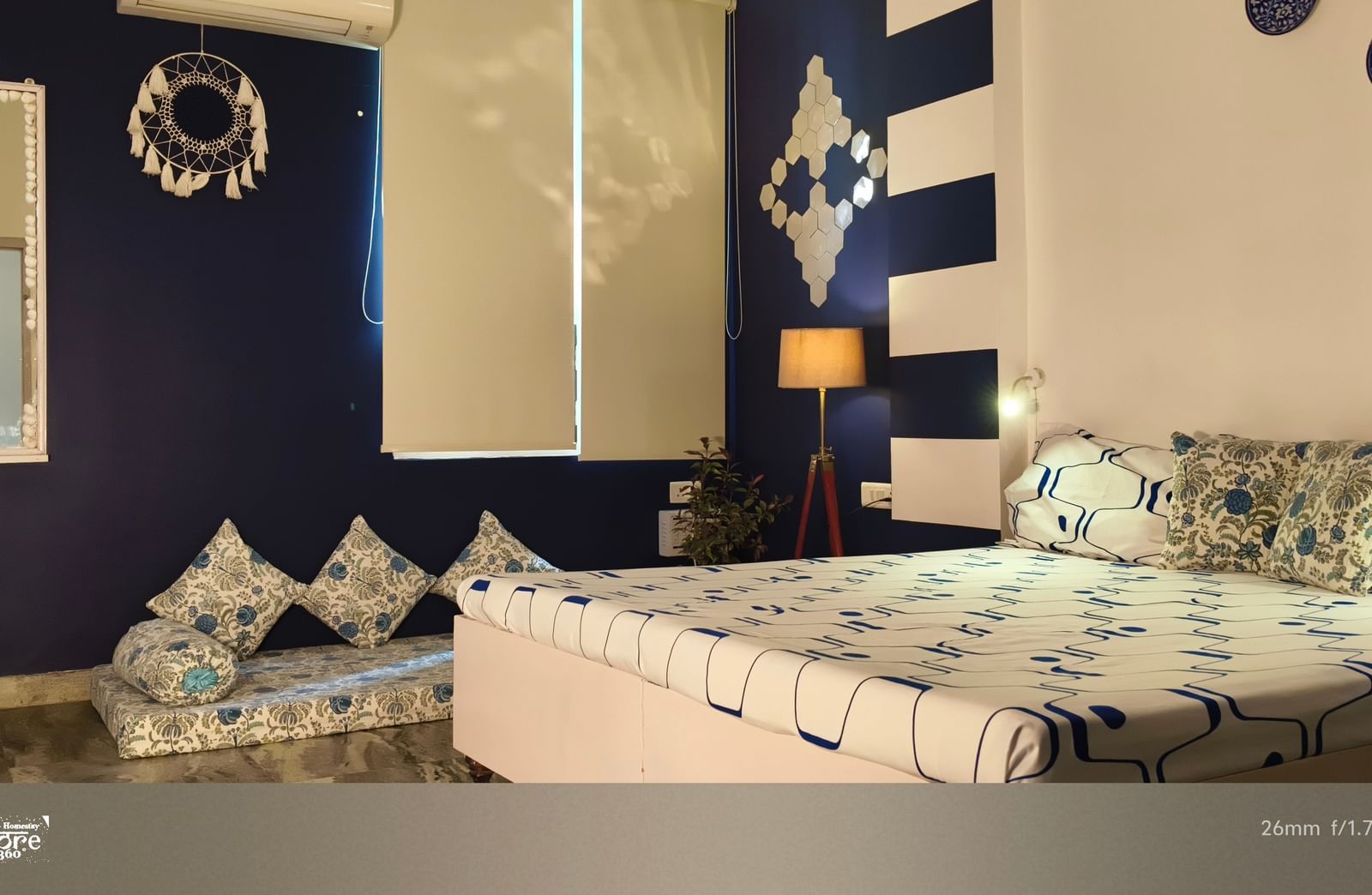 A bedroom with a double bed, patterned bedding, cushions, chairs and a decorative wall backdrop at Jaypore360 Homestay - Best Rooms in Jaipur.