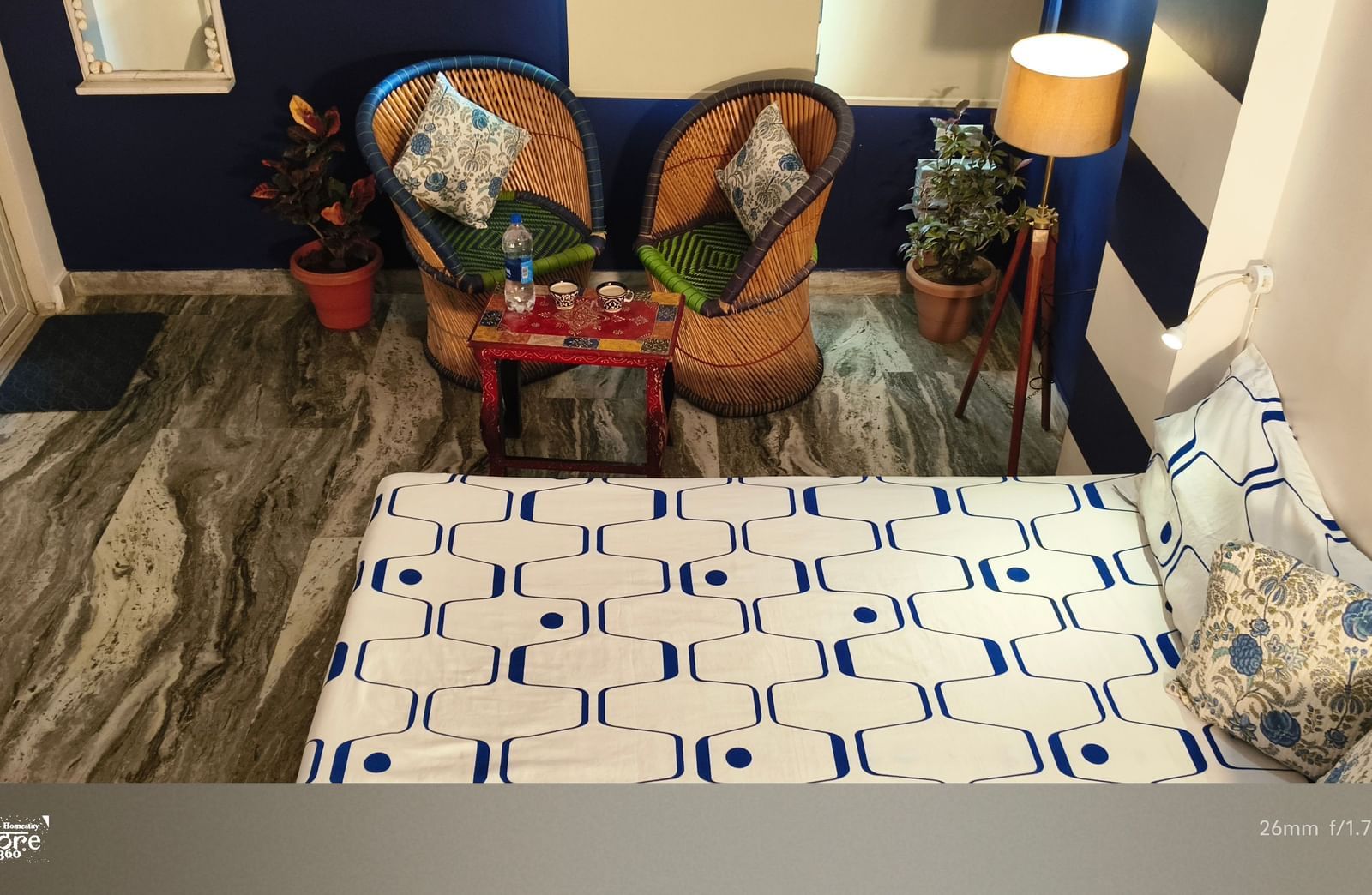 A bedroom with a bed, patterned bedspread, decorative pillows, chairs and plants in the corner at Jaypore360 Homestay - Best Rooms in Jaipur.