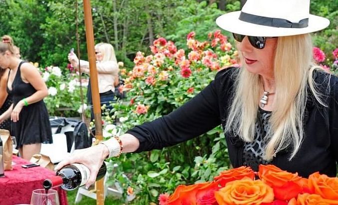 A woman pouring a drink into a glass for a guest during a festival - Brewery Gulch Inn & Spa