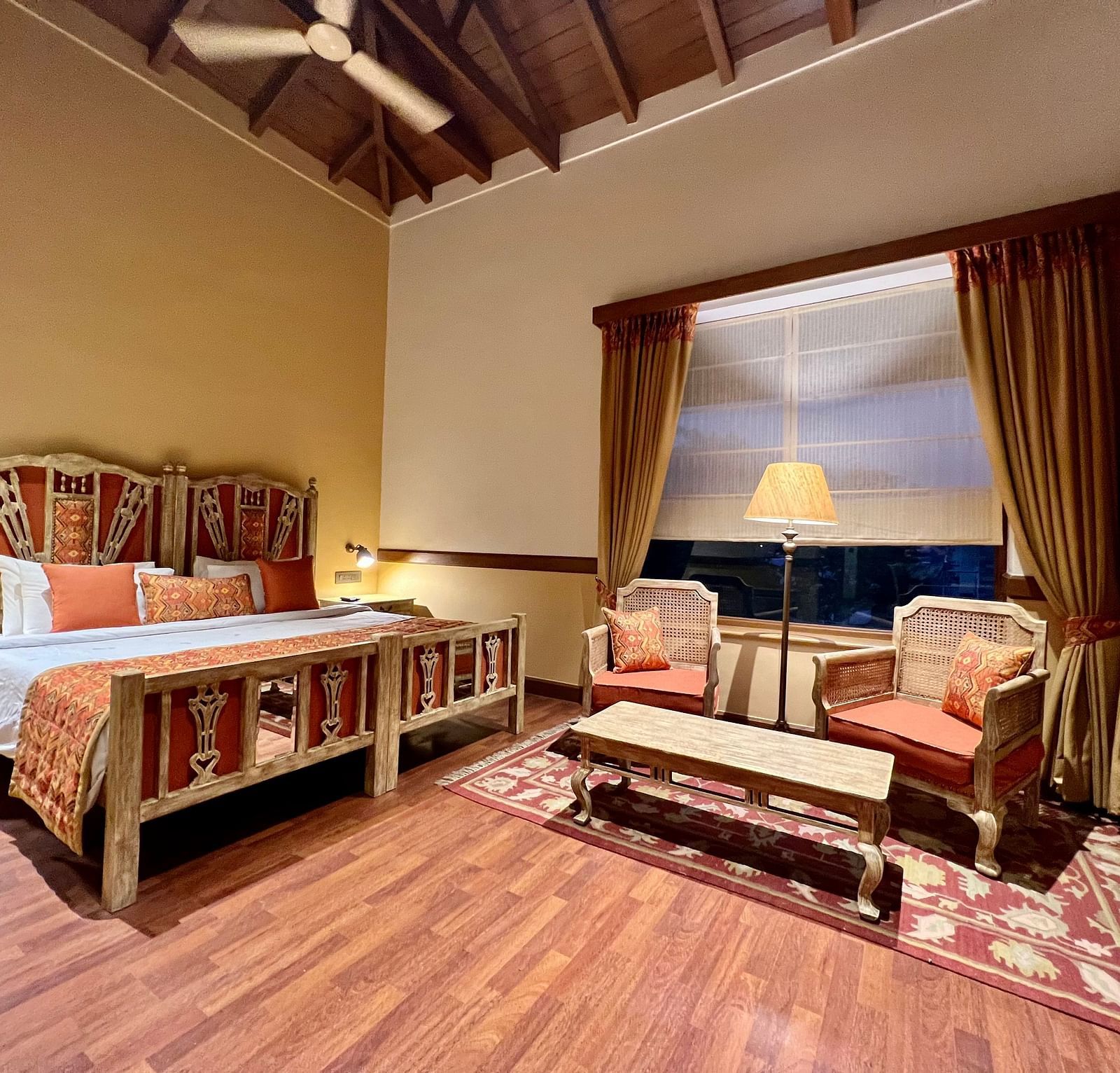 A cozy Superior Lake Facing Room at Fishermen's Lodge, Bhimtal, featuring a comfy bed, sofa, and table, perfect for relaxation.