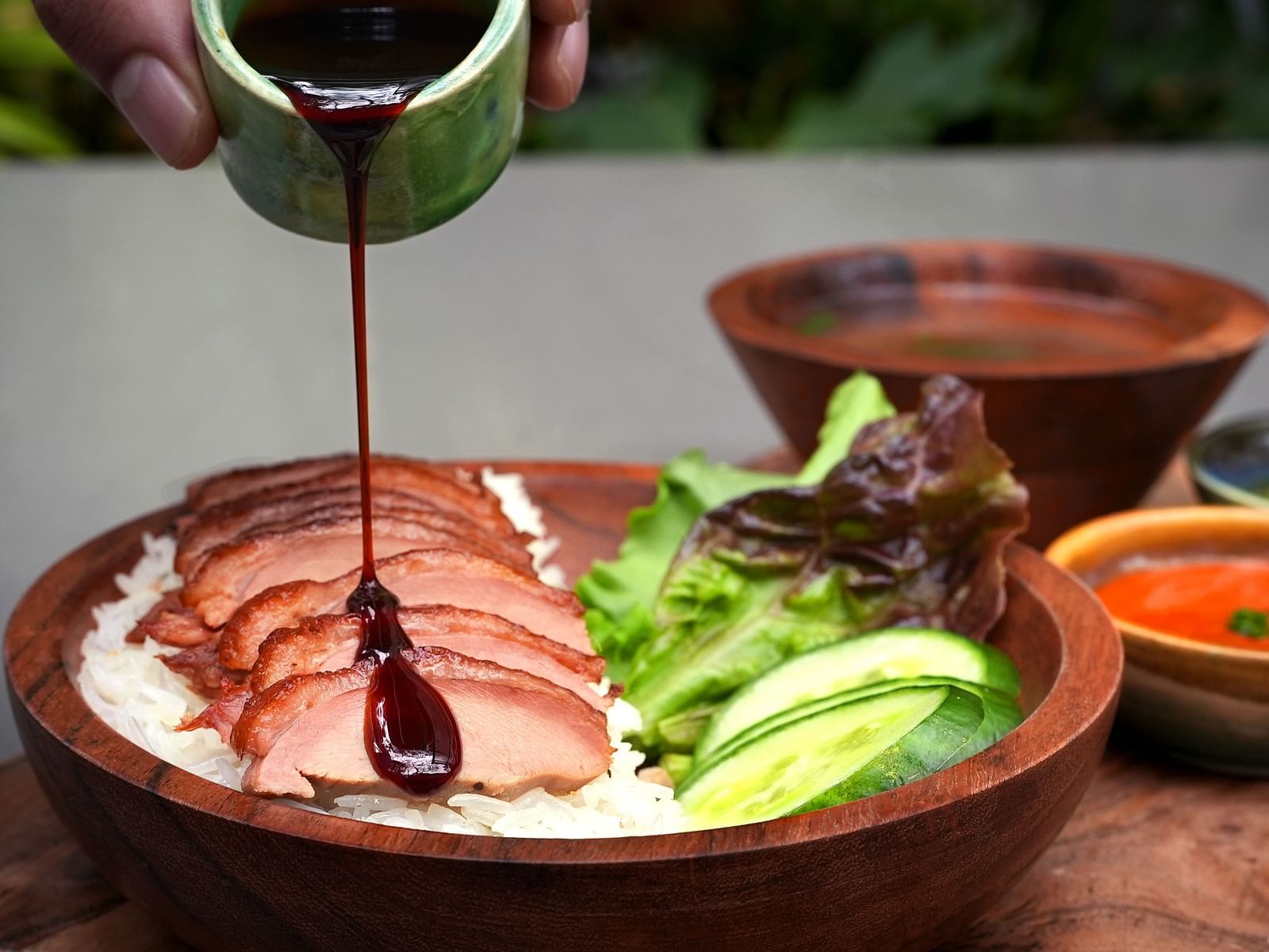 sauce being poured on Hainanse Duck with dip on the side at Village 36