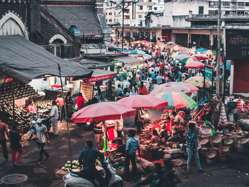 Busy street market with colourful umbrellas and bustling crowd.