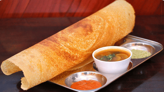 Dosa served with three types of chutney – green, red, and white.