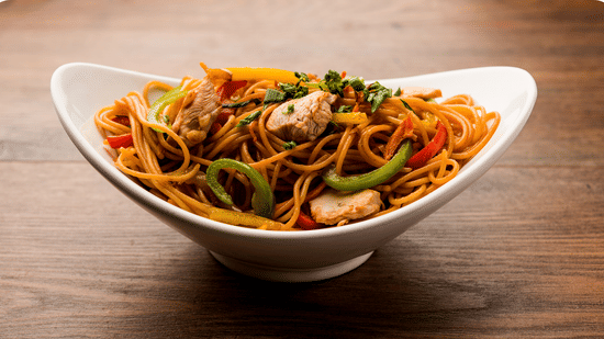 Bowl of stir-fried noodles with vegetables.