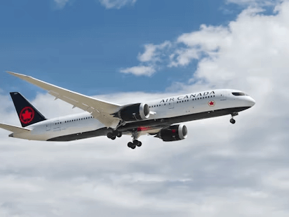 A large passenger airplane is captured mid-flight against a blue sky with clouds.