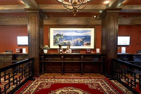 Reception desk with wooden pillars, a framed painting and a red patterned carpet