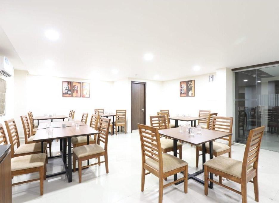 The interiors of Aranaya Restaurant at Pravasa Stay, Ahmedabad (Alba Premier), featuring well-arranged dining tables.