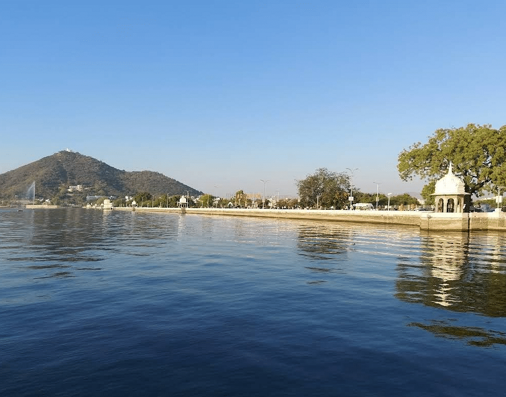 Lake with distant hill, building with dome with reflections on water.