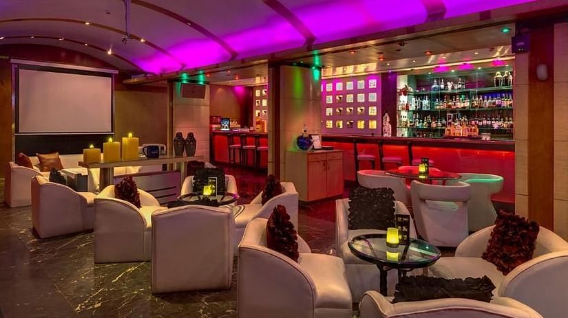 Chic lounge bar with vibrant lighting, plush seating, and a well-stocked bar – Hotel Hindusthan International, Kolkata.