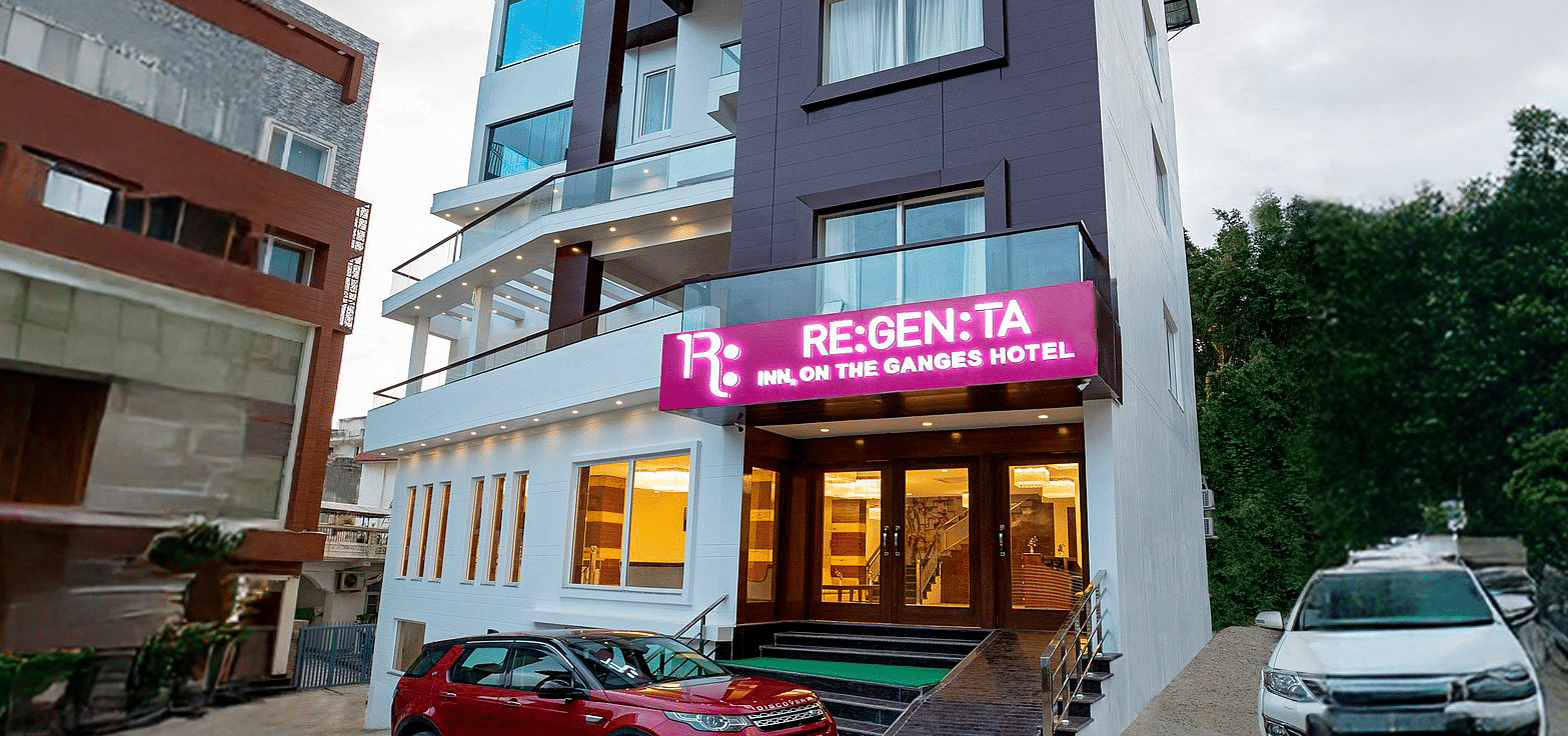 A wind angle shot of Regenta Inn DLS with a lush green hilly region in the background.