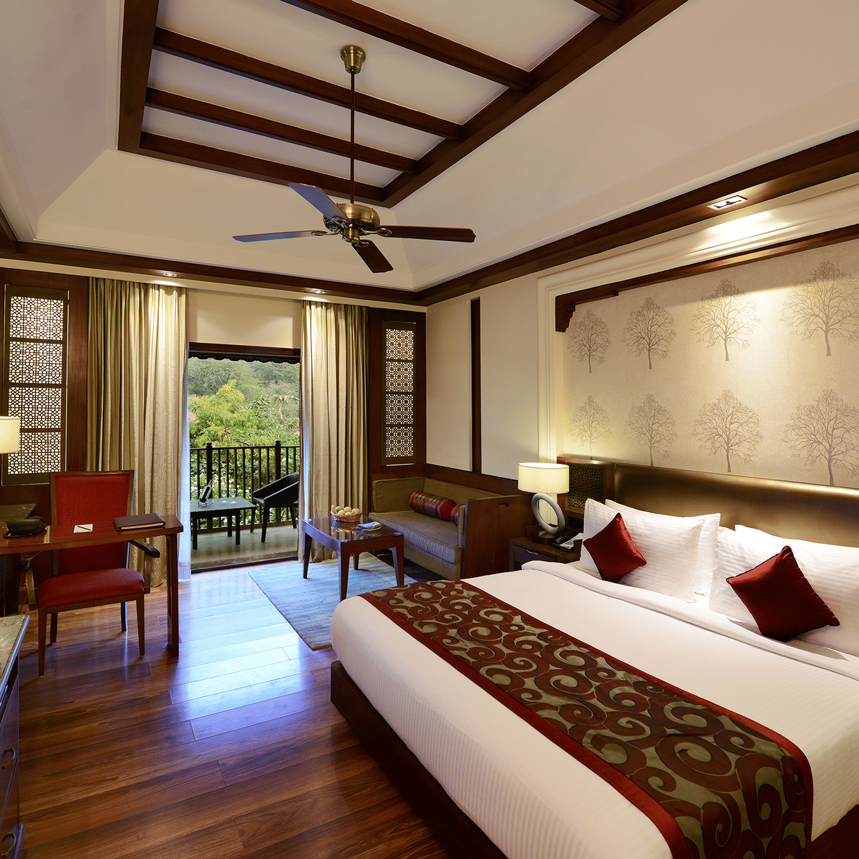 The interiors of our luxury cottages in Ananta Spa and Resort, Pushkar featuring a balcony, a comfortable bed, a desk and a television 