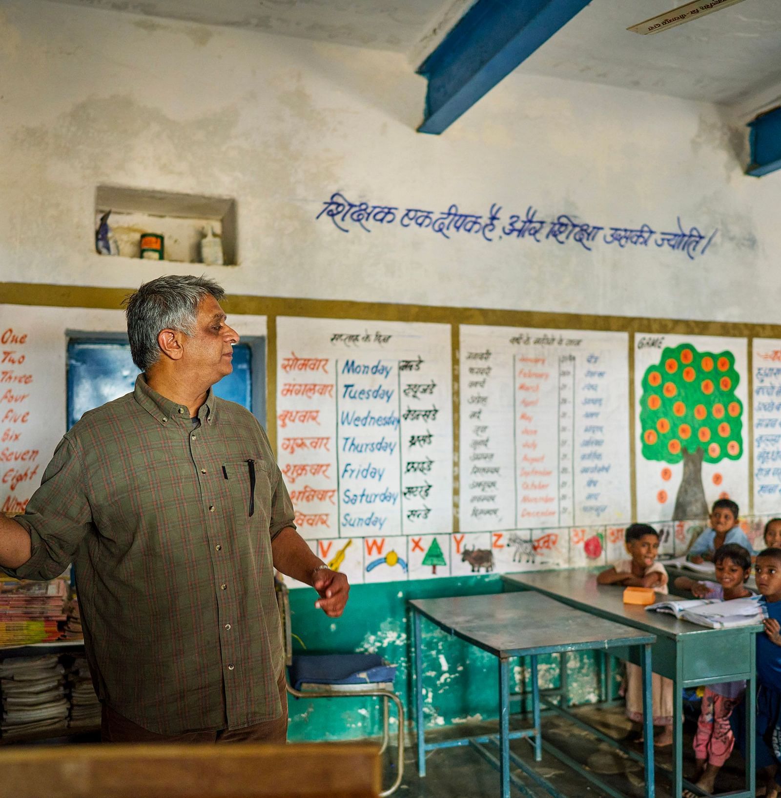 image of an old man teaching with the help of a chalk and blackboard to the students