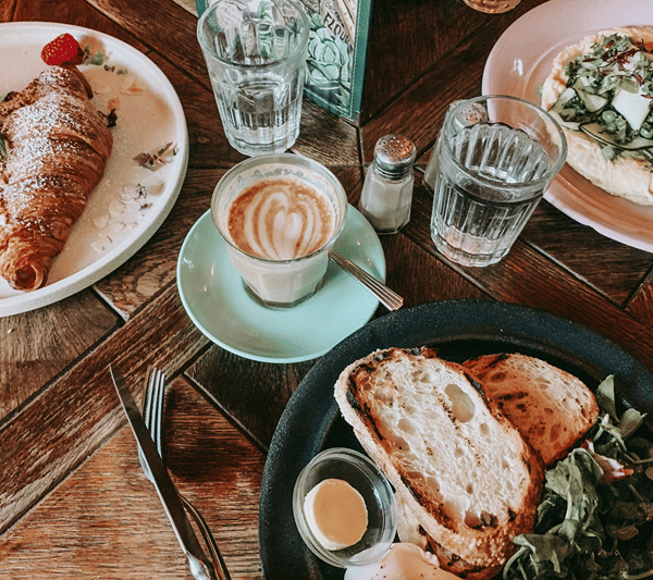 Breakfast table with a croissant, cappuccino, toast and salad.