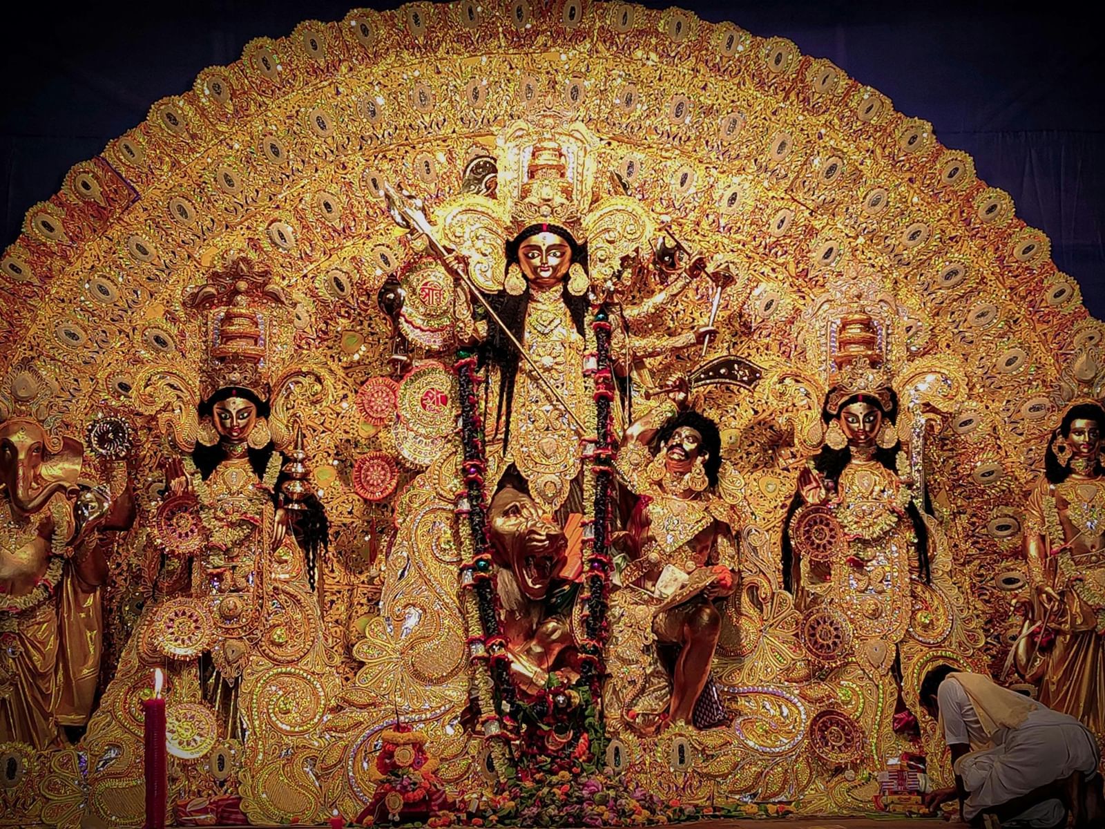 A idol display for Durga Puja featuring Goddess Durga and other deities in an ornate, gold-embellished setting