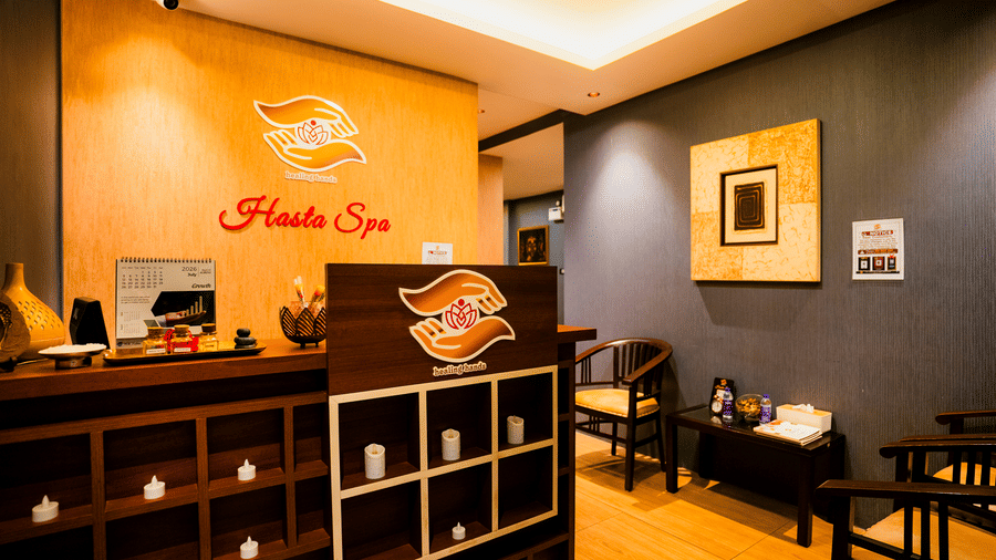 Hasta Spa reception with the healing hands logo on a timber wall, oil bottles on the counter and waiting chairs at Ilara Hotels & Spa, Tada.