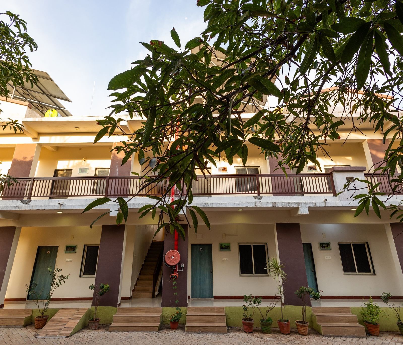 A view of the facade featuring rows of guest rooms with a wide balcony area surrounded by greenery at Daksh Resort and Amusement Park.