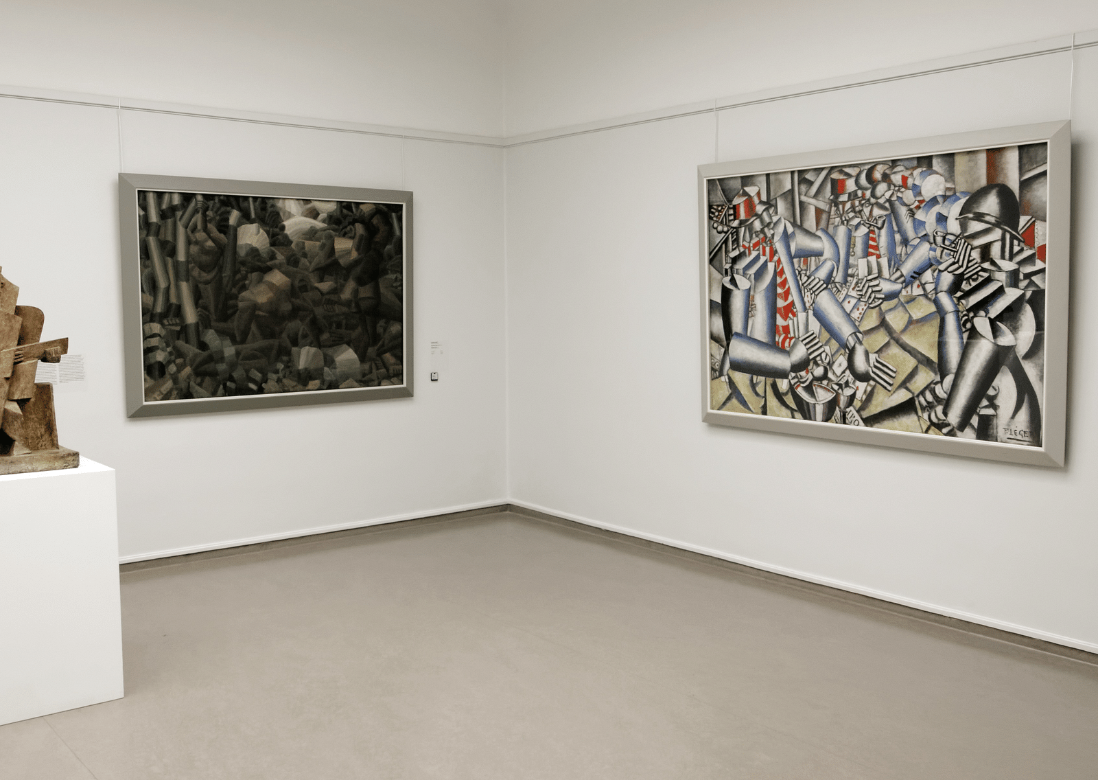 An overview of a museum with paintings hung on the wall and a sculpture on a stand.