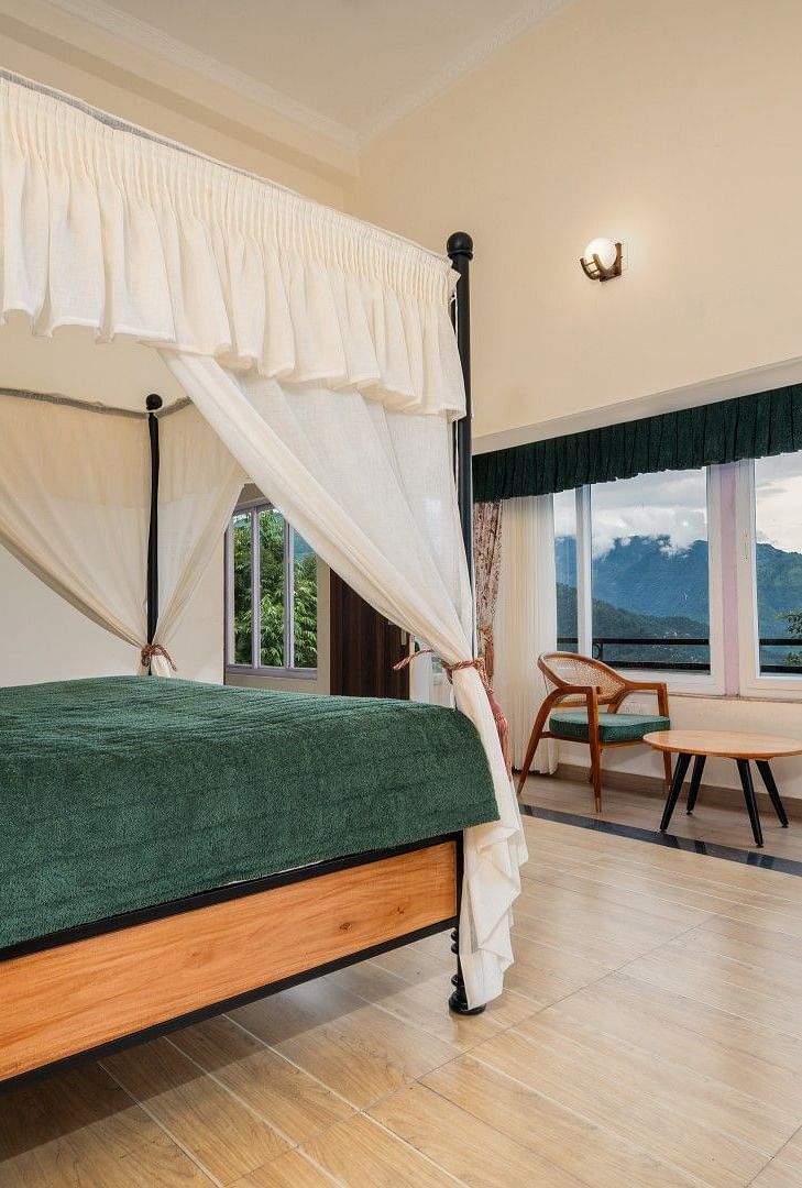 Premium Suite with Balcony features a large windows along with generously sized bed with well-lit illumination, accompanied by wooden furniture