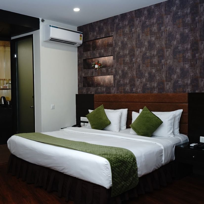 A Deluxe Room featuring a double size bed, bedside table on either side,  flat TV screen, AC, fruit basket and bouquets, and tea and coffee maker at Five Elements Hotels North Avenue, Delhi