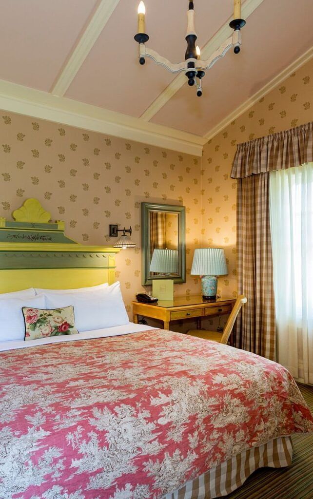 A charming and comfortable guest room at the Tallman Hotel, with a sloped ceiling, a double bed, and elegant decor.