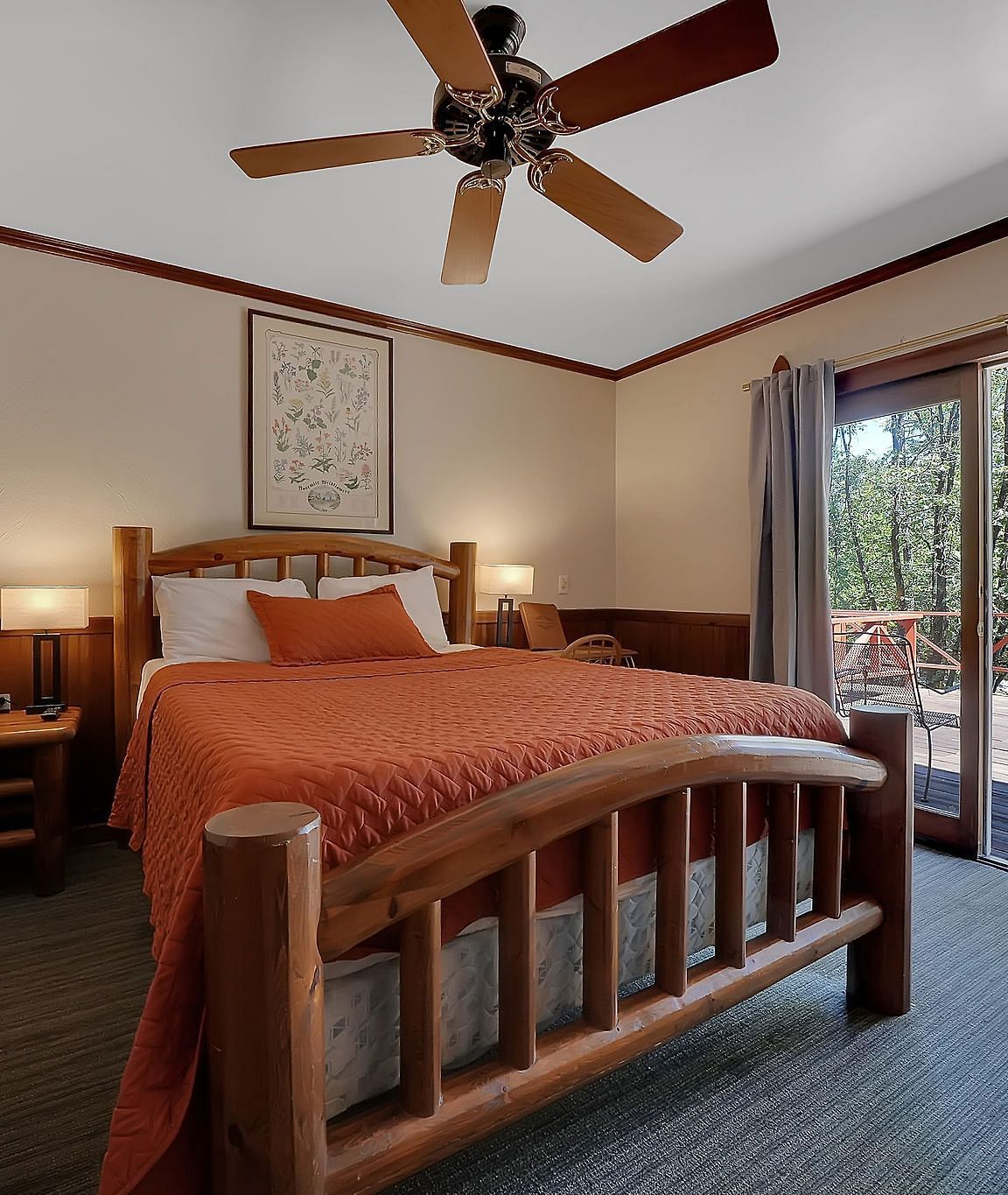 A view of a room at Narrow Gauge Inn with a double bed and sliding doors opening up to an outdoor patio.