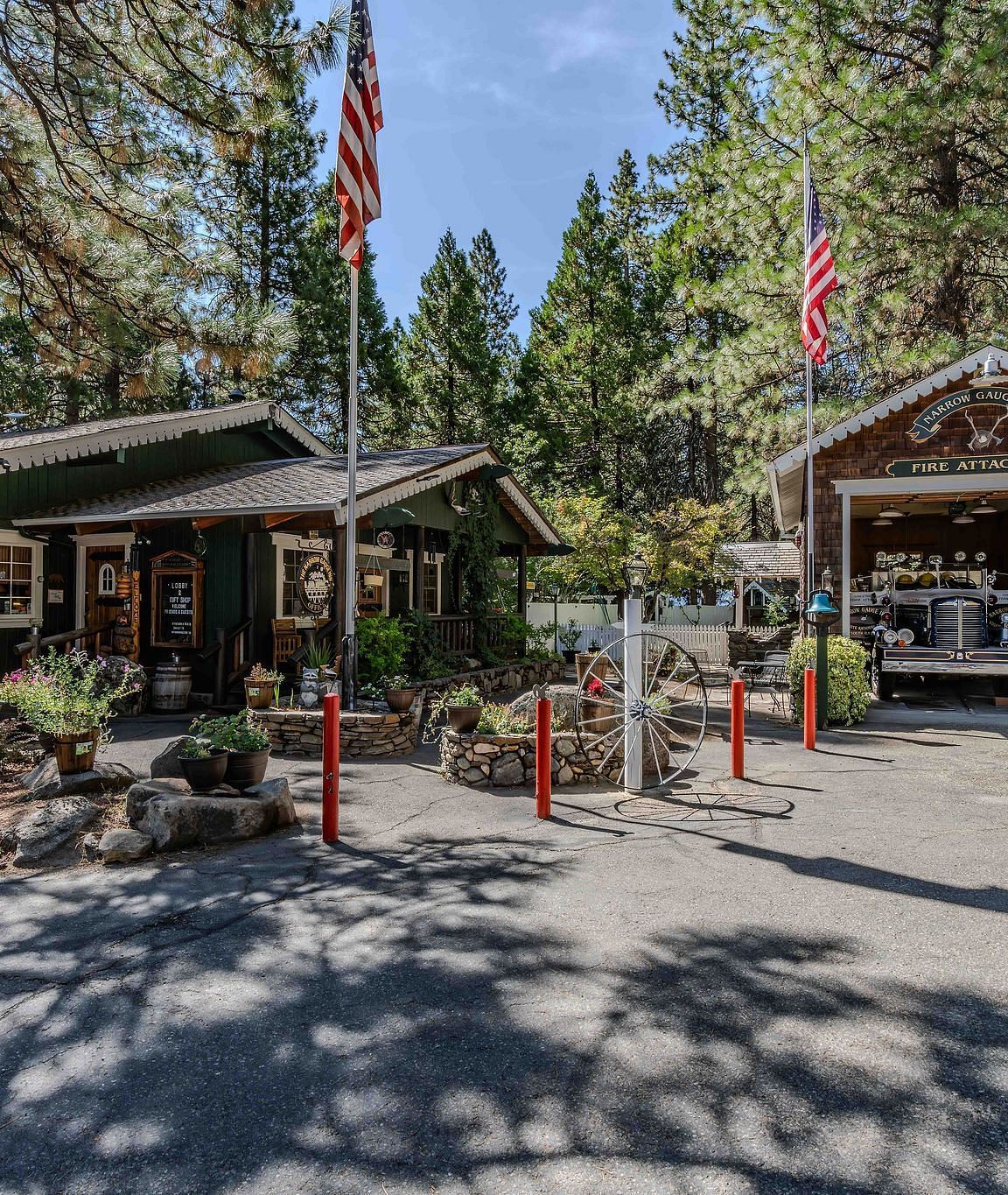 Exterior of a few wooden cabins at Narrow Gauge Inn with trees in the backdrop on a clear, blue day.