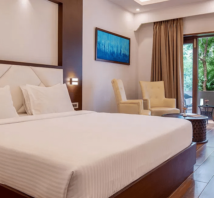 Spacious hotel room with a king-sized bed, modern furnishings, and a balcony