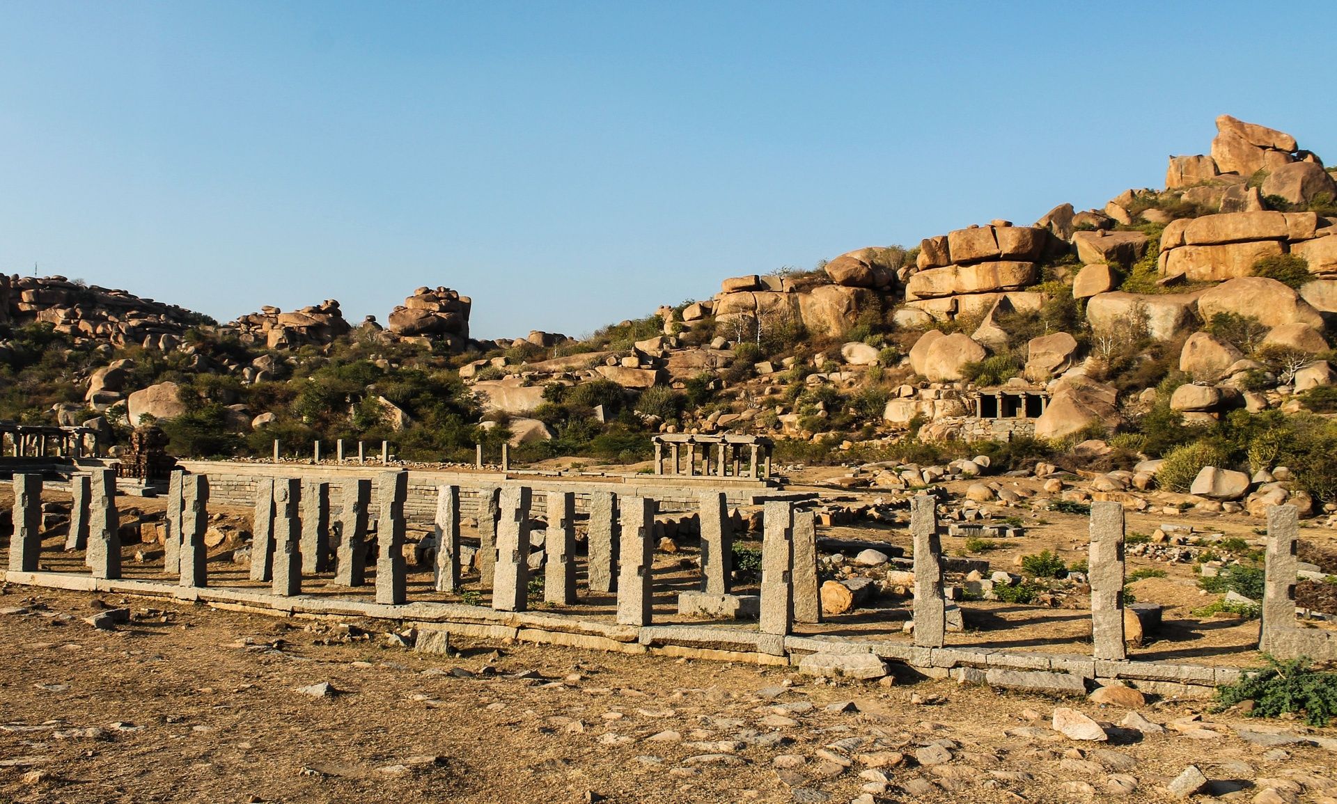 Ancient stone ruins with pillars and rocky hills.