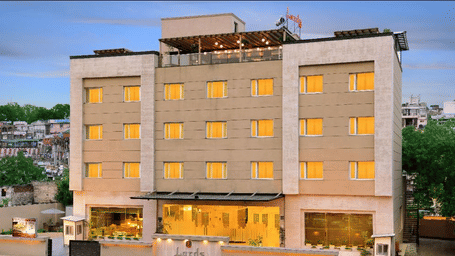 A beige hotel building with a few lights on and a sign on the roof.