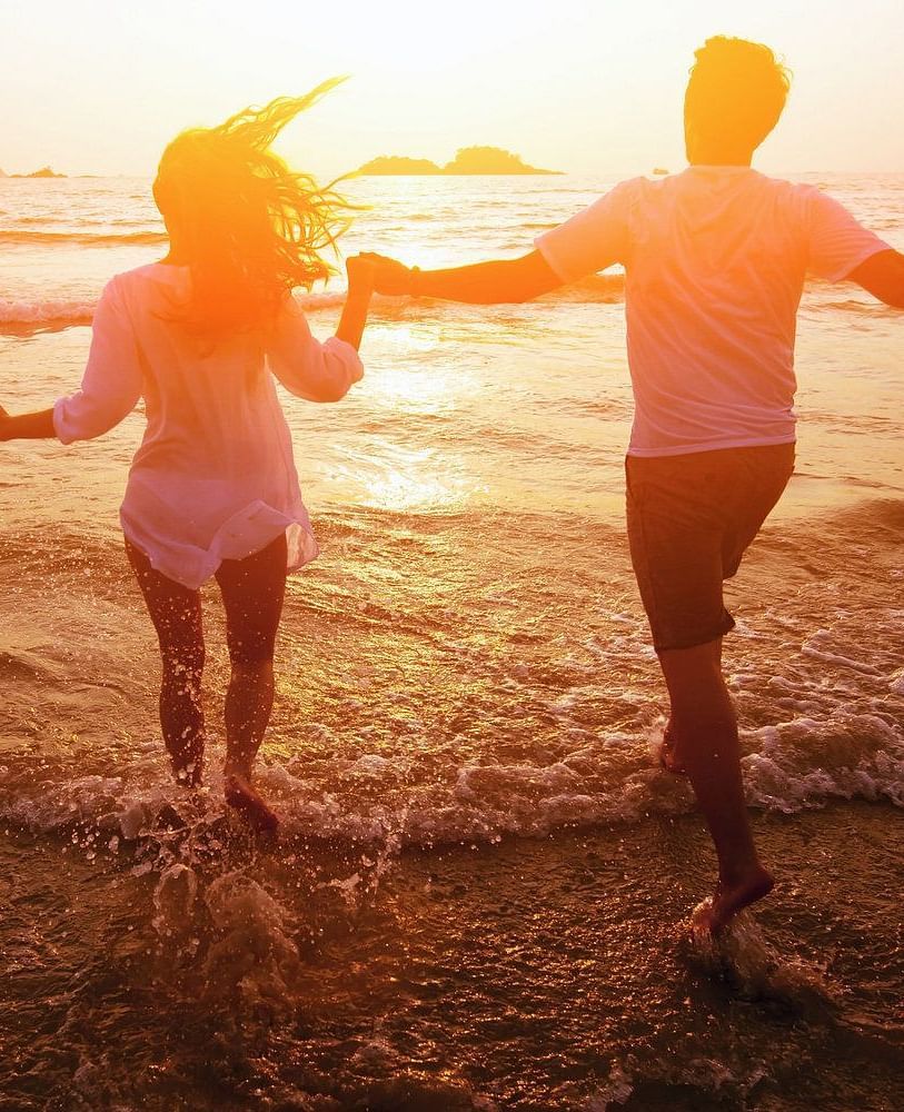 A couple walking hand in hand into the water at the beach during a susnset - Brewery Gulch Inn & Spa