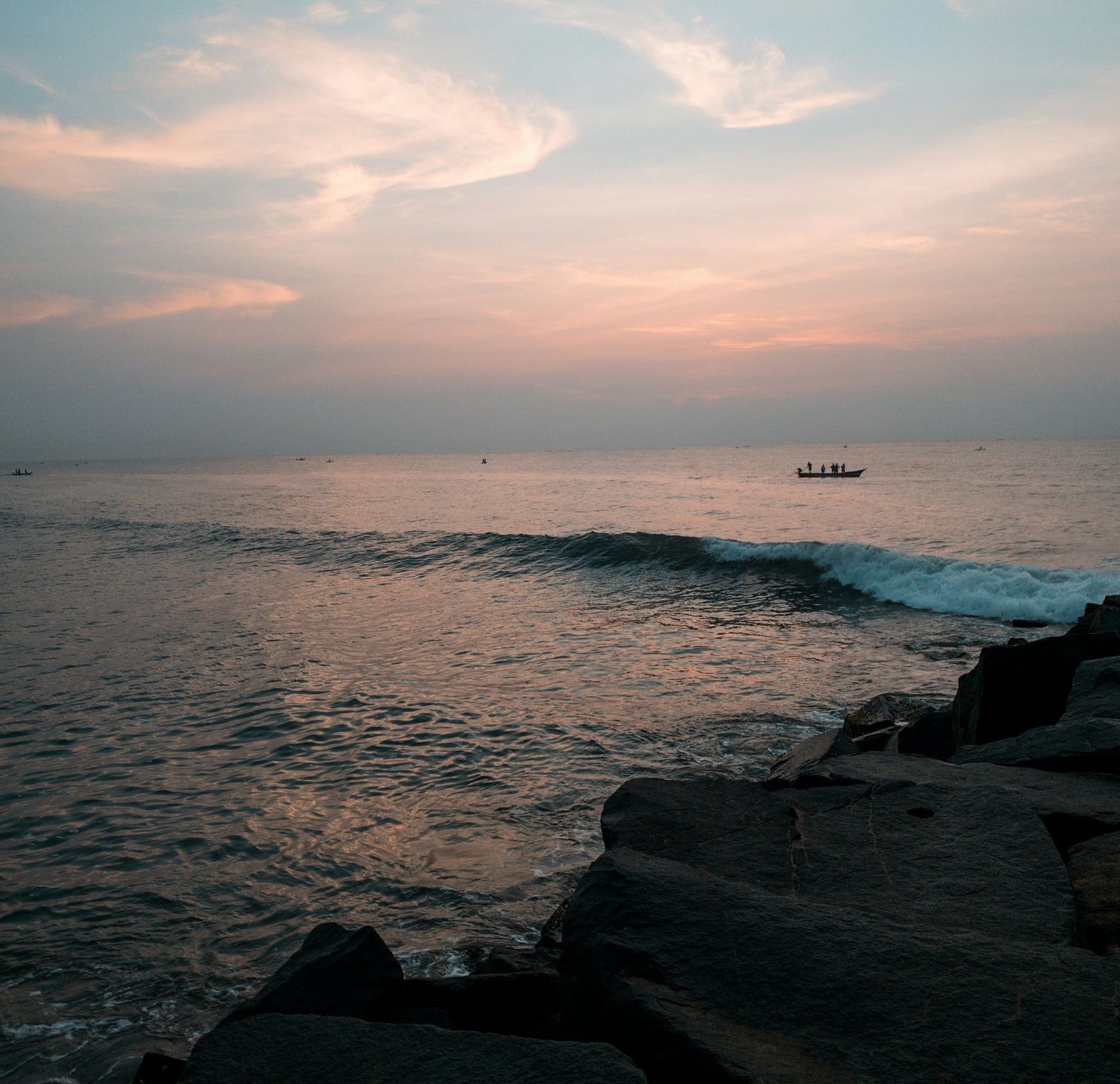An overview of a beach in Pondicherry with a boat travelling on the waterbody