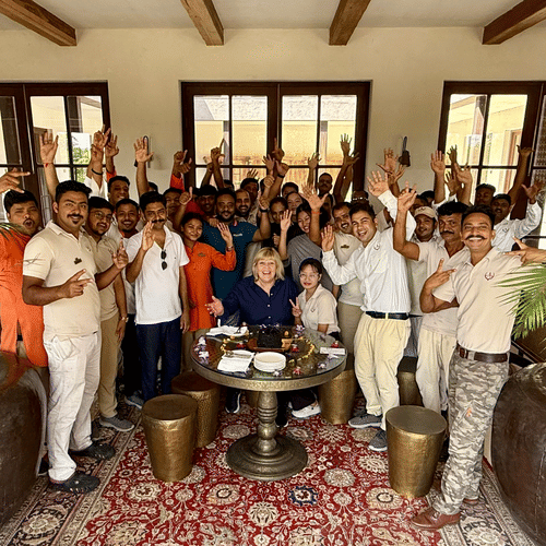 Aramness Gir team members gathered in an indoor lounge, smiling and raising their hands in celebration.